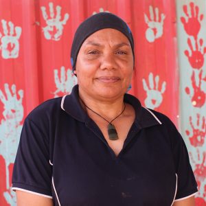 Leah Leaman Yinpingali Namitja, who is standing in front of an artwork and smiling.