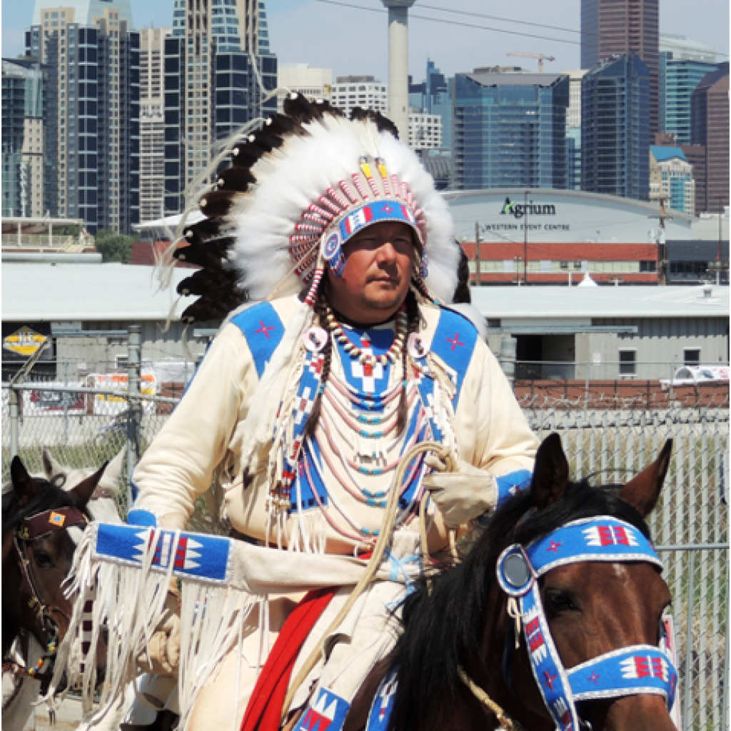 Kent Ayoungman in ceremonial dress, riding a horse.