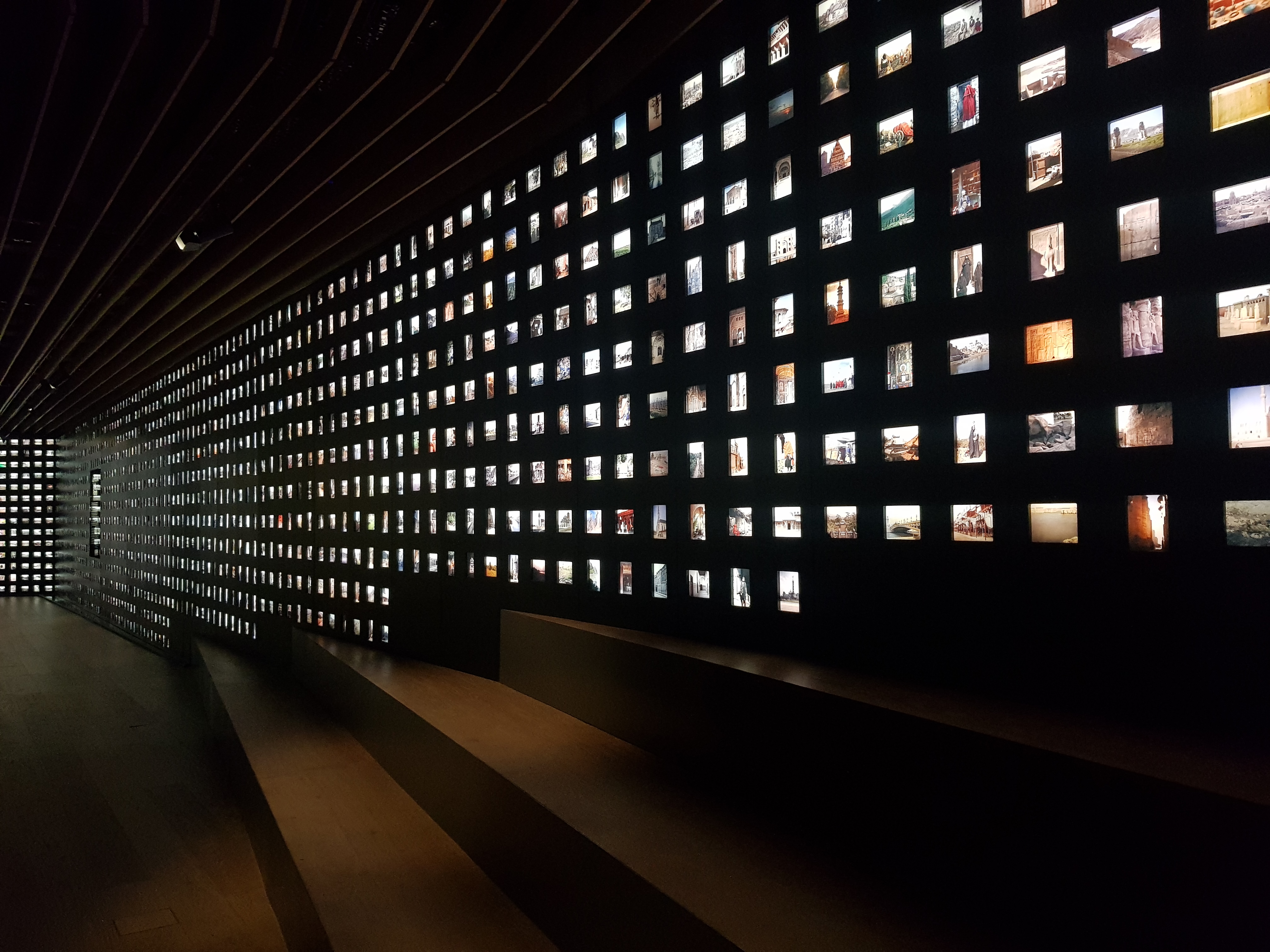 Interior view of a museum showing a wall display of illuminated slides