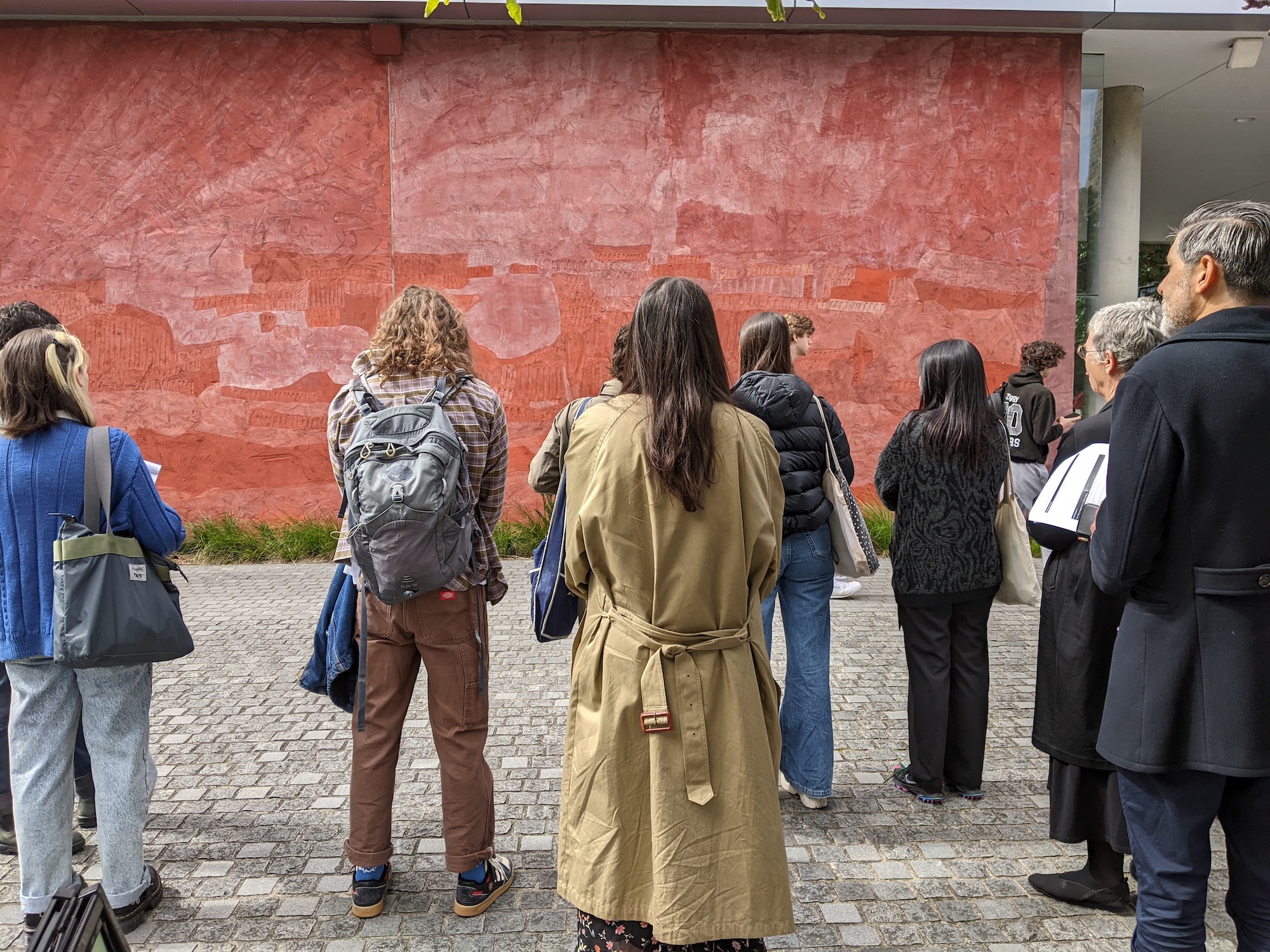 A group of people stand with their backs to the camera, facing a mural