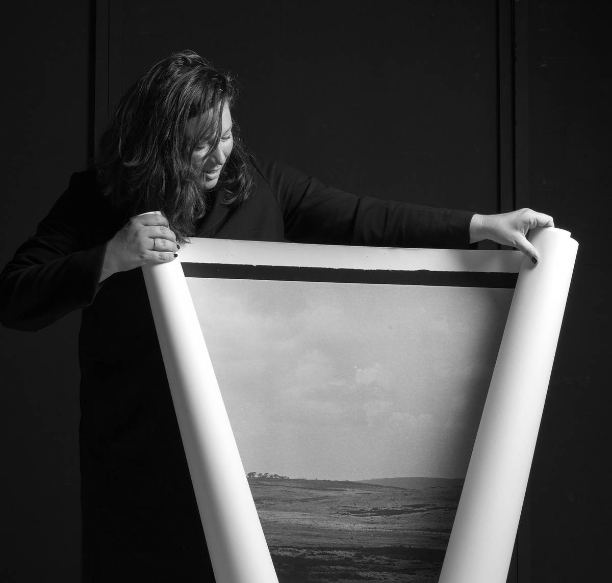 A photograph of a woman unrolling a large photograph