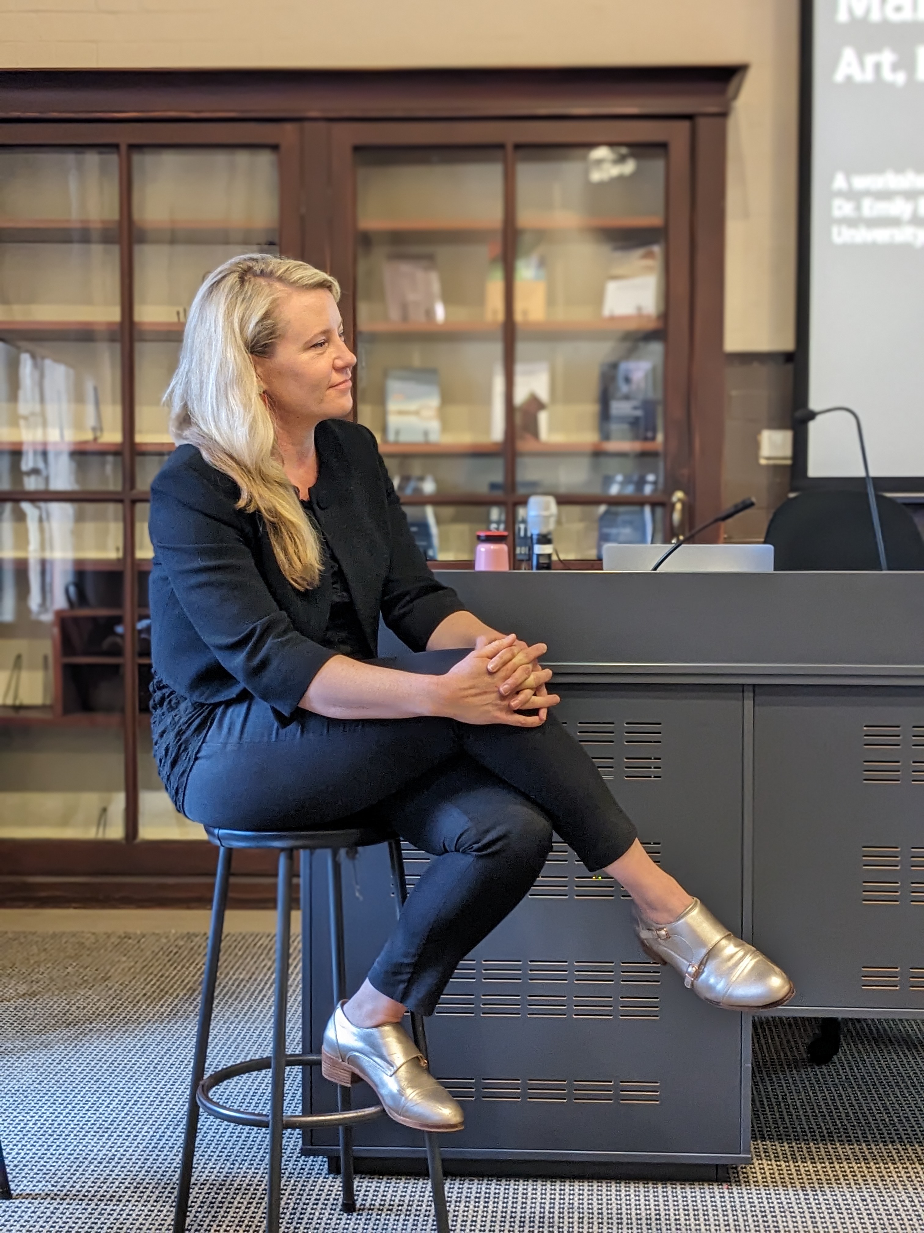 Emily Brink sits on a stool facing to the right.