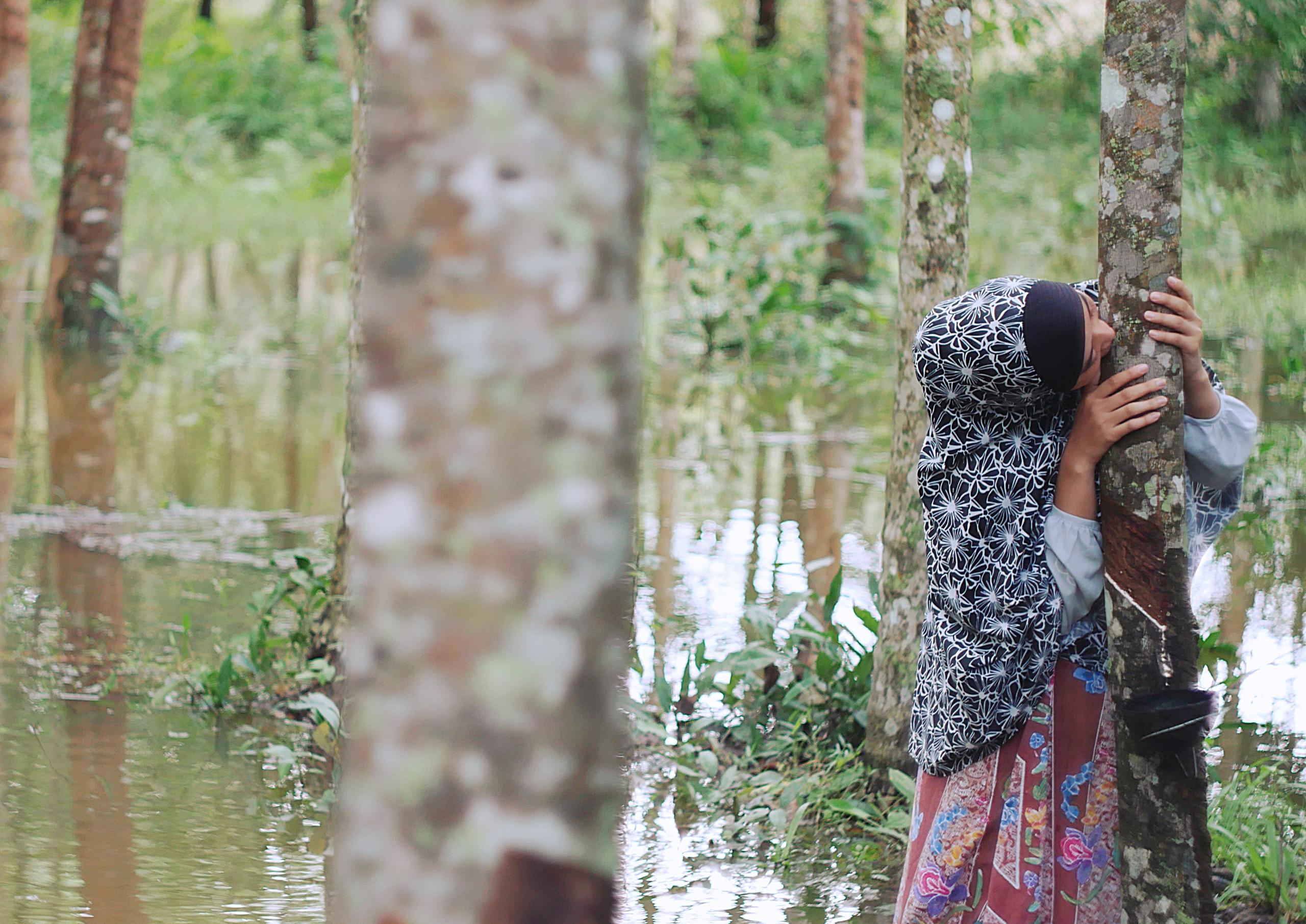 A woman with her face against a tree.