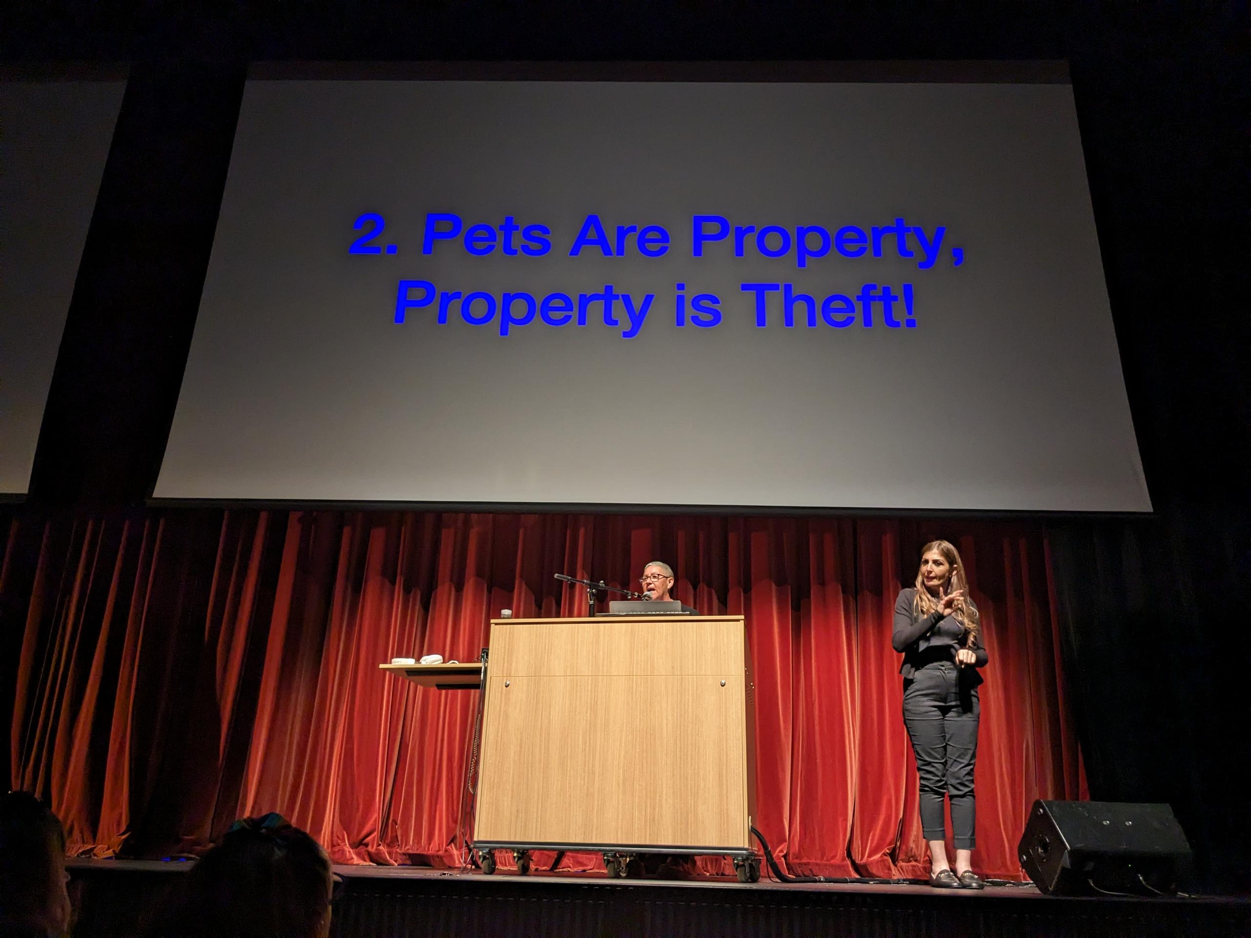 Jack Halberstam at a lectern delivering a PowerPoint presentation. The slide behind him reads "Pets Are Property, Property is Theft!"