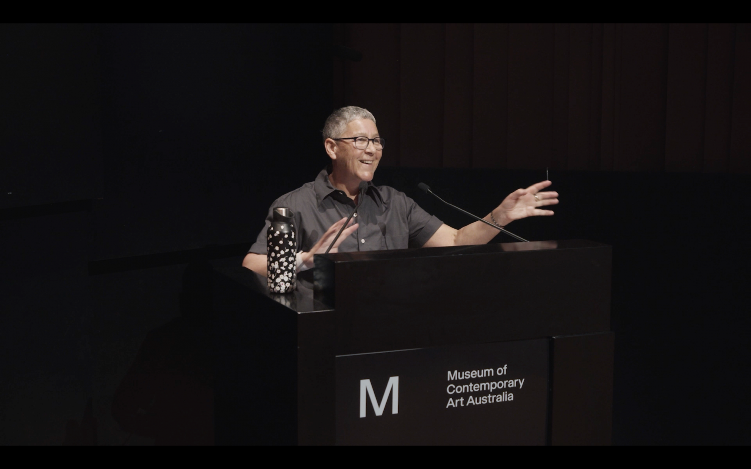 Jack Halberstam at a lectern delivering a lecture. He is smiling and gesturing with his hands.